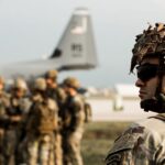 Swirling fractal spiral rendered in vibrant violet and cyan tones against a dark background, forming an abstract kaleidoscopic vortex.