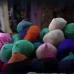 A young woman wearing a black VR headset is immersed in a virtual reality experience under soft pink and blue neon lighting in a dimly lit room.