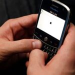 Modern glass office tower reflecting warm orange and pink sunset colors in its mirrored facade
