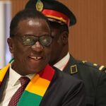 Contemporary broadcast studio featuring a large curved LED screen wall showing breaking news graphics and world map in blue and red tones