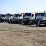 Long queue of Sudanese families with children and jerrycans waiting for emergency food and water distribution in a dusty North Darfur camp