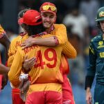Australian left-arm paceman Mitchell Starc mid-delivery stride, eyes locked on the stumps, Zimbabwe opener at the non-striker’s end, night-match floodlights blazing at the ICC Men’s T20 World Cup 2026
