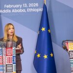 Ethiopian Prime Minister Abiy Ahmed and Italian Prime Minister Giorgia Meloni shake hands and smile while standing side-by-side on a red carpet in front of Ethiopian and Italian flags during an official diplomatic meeting in Addis Ababa