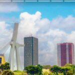 A bearded father in a navy hoodie and his young son in a gray sweater share a quiet loving embrace while seated on a wooden park bench