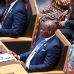 Smiling couple toasting with glasses against golden sunset sky on Valentine’s Day