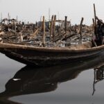Perfectly calm mountain lake at dawn, reflecting snow-capped peaks and golden sunrise sky