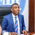 Golden Retriever lying on a rich wooden floor, head raised and looking up with soft, trusting brown eyes