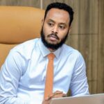 Small golden retriever puppy running through tall grass and wildflowers in early morning sunlight