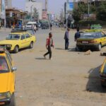 Close-up of an antique leather-bound book with worn spine resting on a dark wooden desk