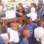 Group of diverse students working together at a desk with laptops and notebooks in a bright classroom setting