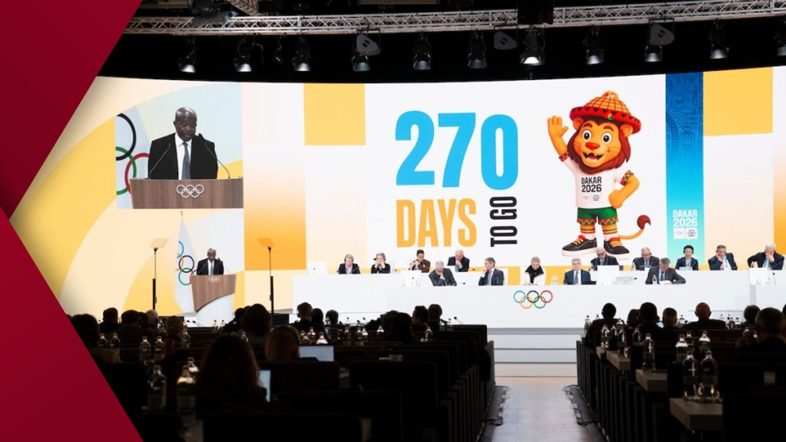 Portrait of Oli, a smiling businesswoman with dark hair wearing a navy blazer against a soft grey background